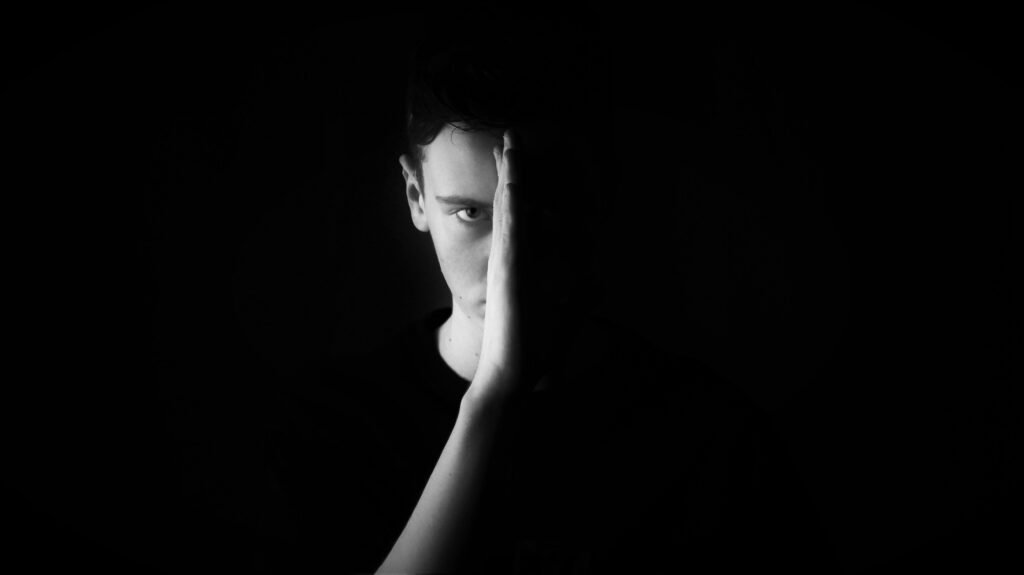 Man hiding half his face behind his hand, a portrait of financial anxiety