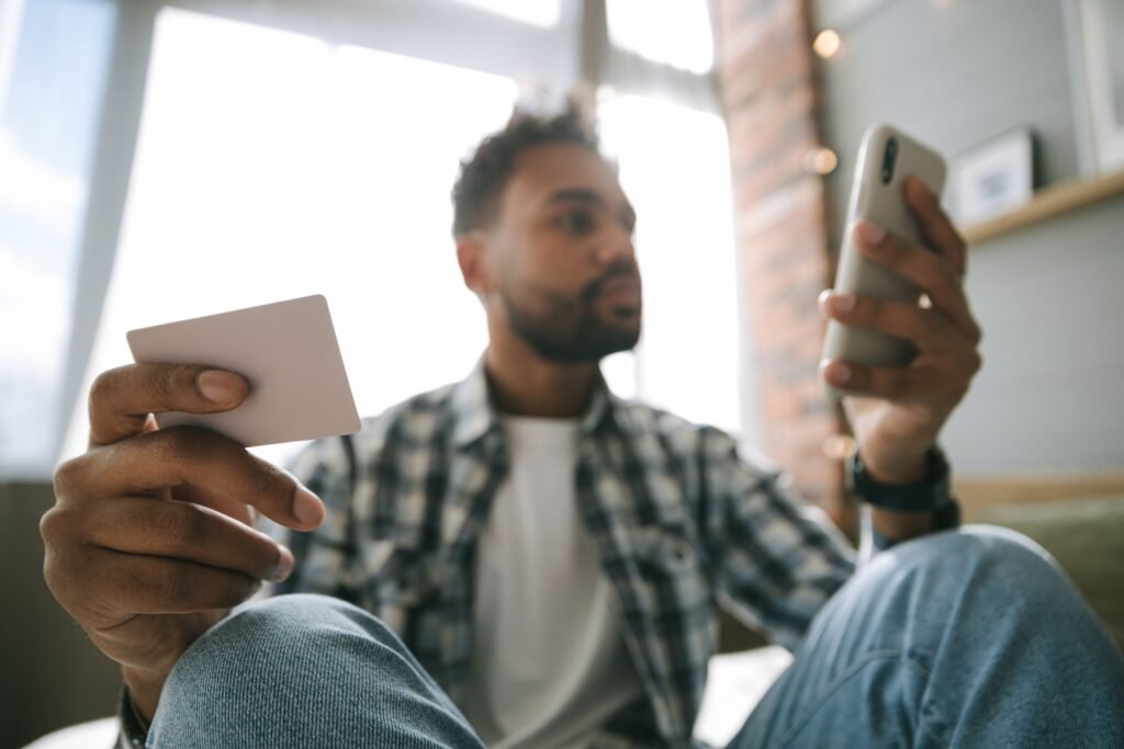 Man holding a bank card and a phone, comparing a savings account vs checking account
