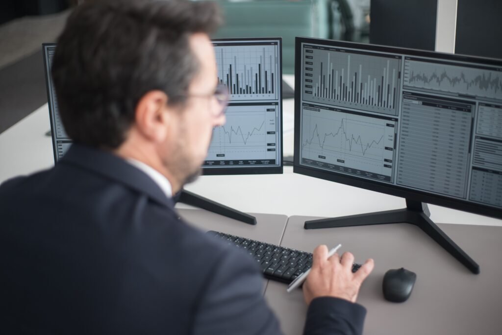 Investor studying market charts on two monitors before deciding on dollar-cost averaging vs lump sum