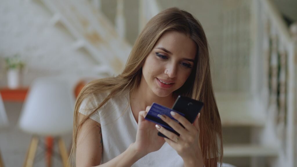Woman checking a credit card on her phone, weighing a credit freeze vs credit lock