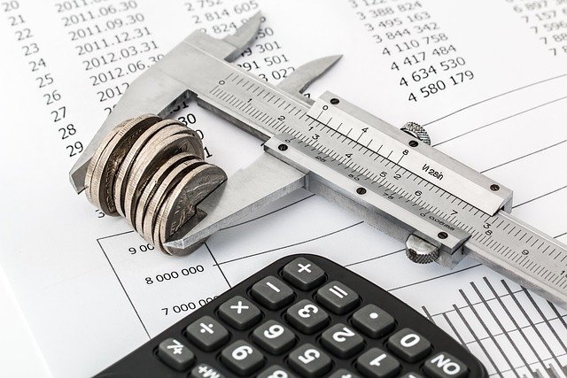 Coins under calipers beside a calculator, weighing money market account fees and minimums
