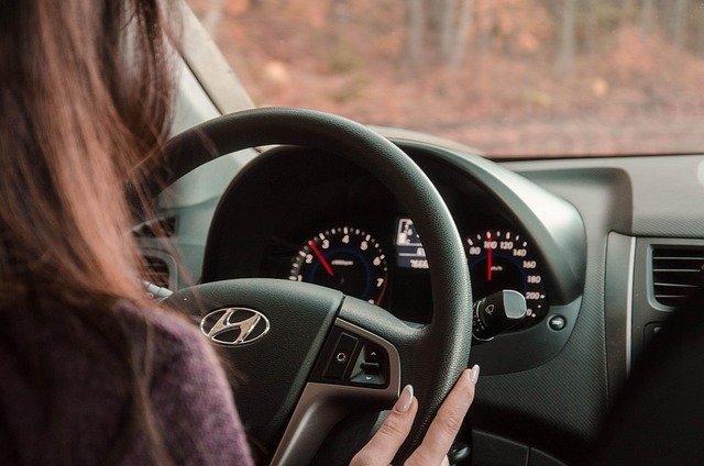 Driver's hands on a steering wheel and speedometer, mileage that matters in lease vs buy a car