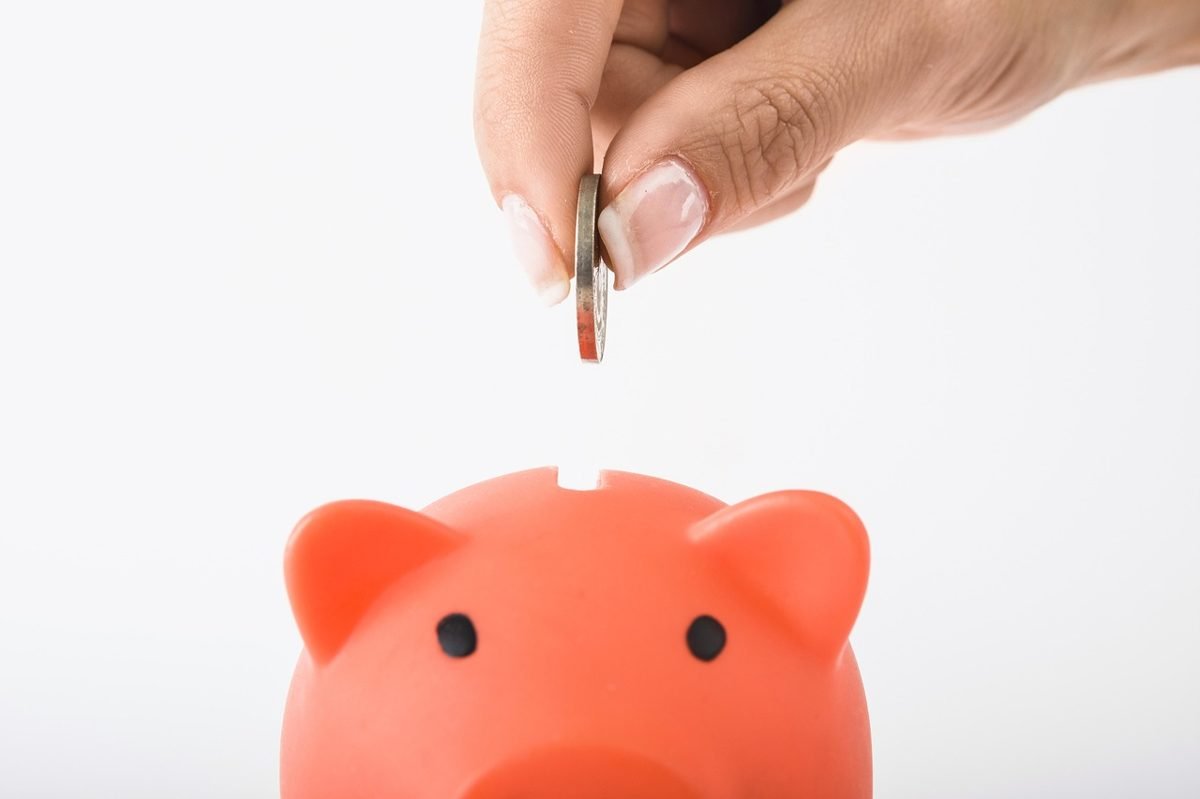 Hand dropping a coin in a piggy bank to cover the waiting period if you need disability insurance