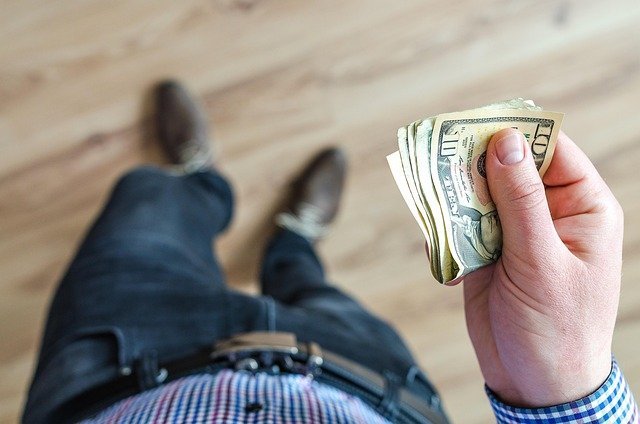 Hand holding dollar bills, the cash you could lose to early withdrawal penalties on a cd ladder
