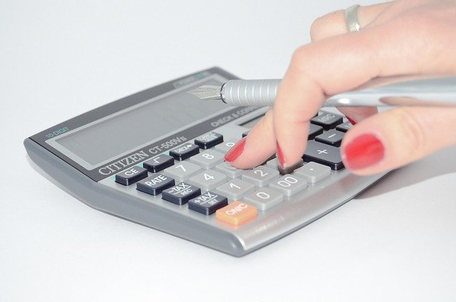 Hand using a calculator to adjust W-4 withholding