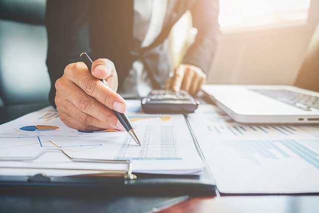 Hand with a pen reviewing documents, the details behind freelance invoicing