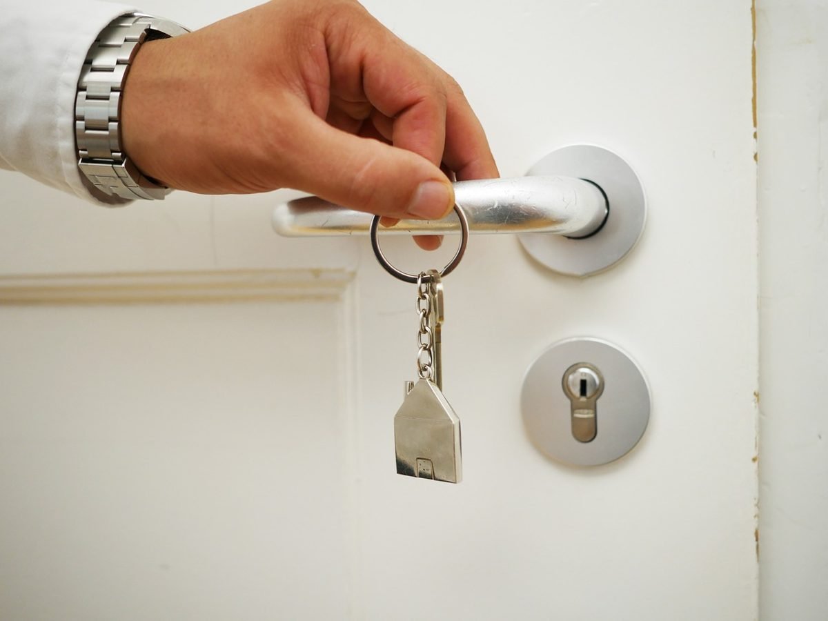 Hand turning a house key in a door after the home closing process
