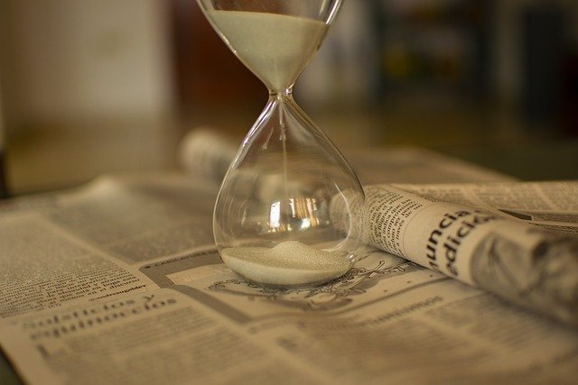 Hourglass on a newspaper, showing how treasury bills pay off at a set maturity date