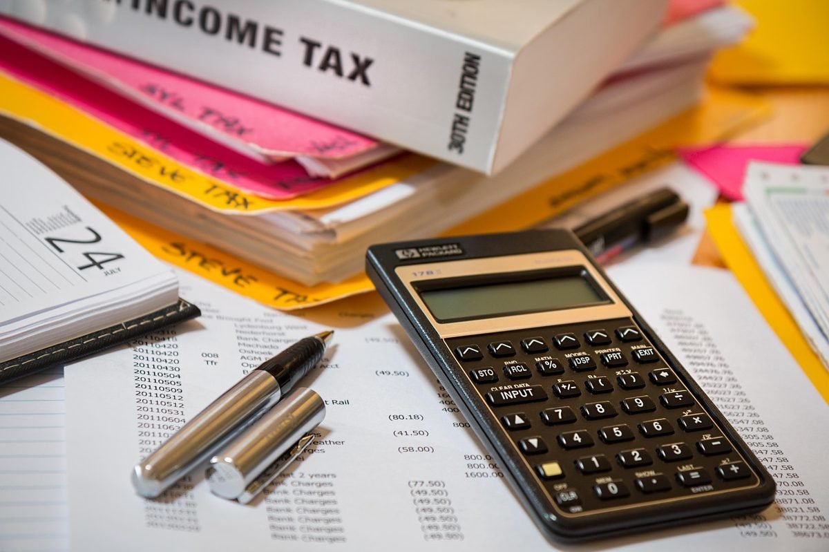 Income tax book, calculator and paperwork for calculating self-employment tax