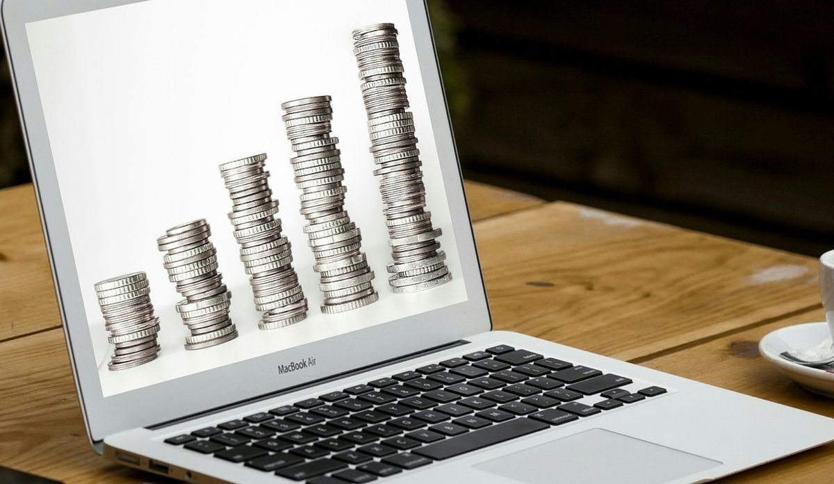 Laptop and coin stacks representing online investing in 2026