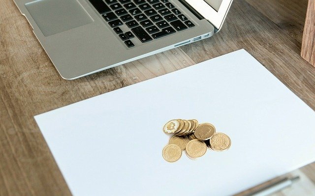 Laptop and coins on a desk, doing the math on passive income ideas