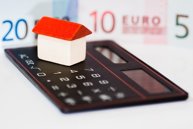 Model house on a calculator, counting the cost of private mortgage insurance