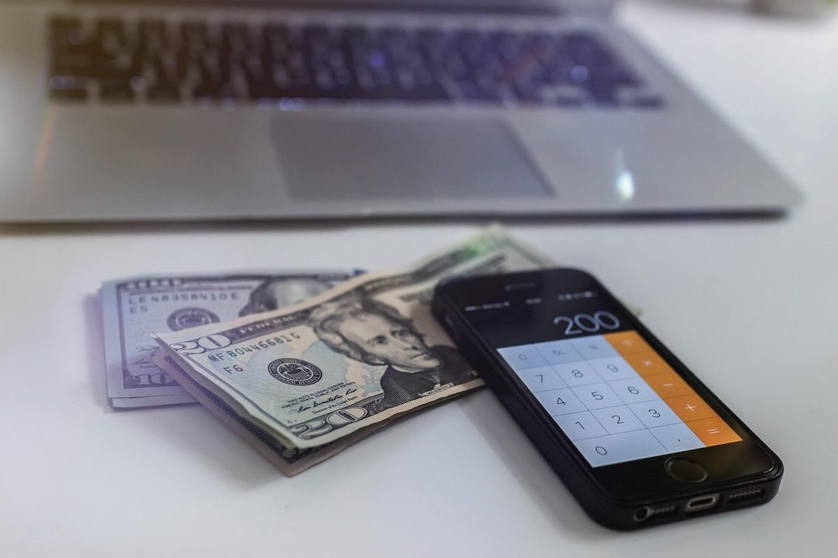 Cash and a phone calculator showing monthly income for a paycheck to paycheck budget
