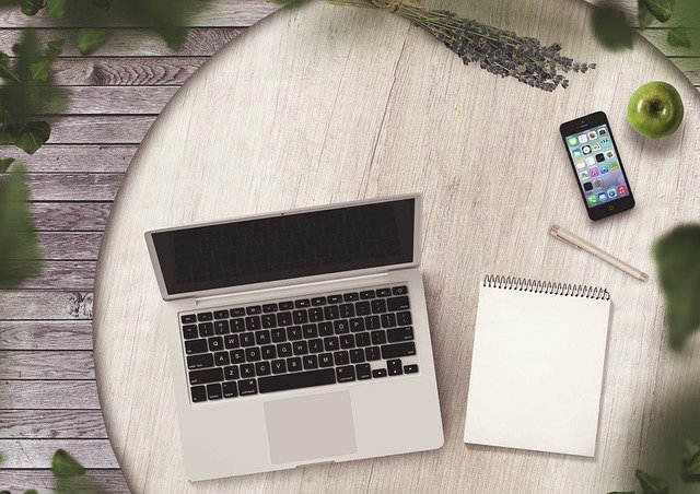 Notepad and phone on a table, a checklist for choosing investment apps