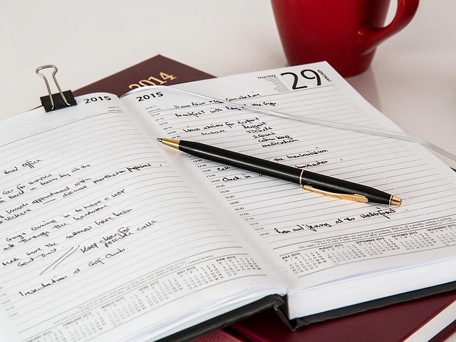 Open diary and pen to plan a side hustle to full-time quit number