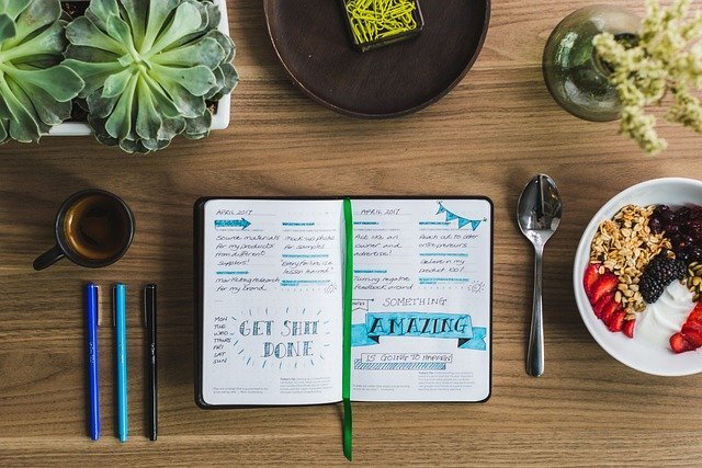 Open journal and pens for a weekly review of your money scripts
