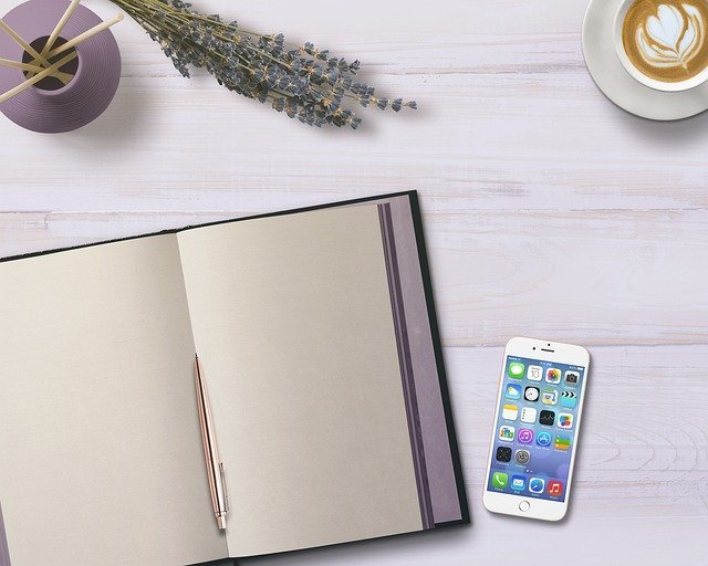 Notebook and phone to plan your contributions after you open a Roth IRA
