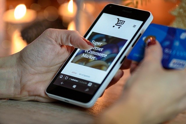 Hands holding a phone and a bank card while shopping, a moment where buy now pay later is offered
