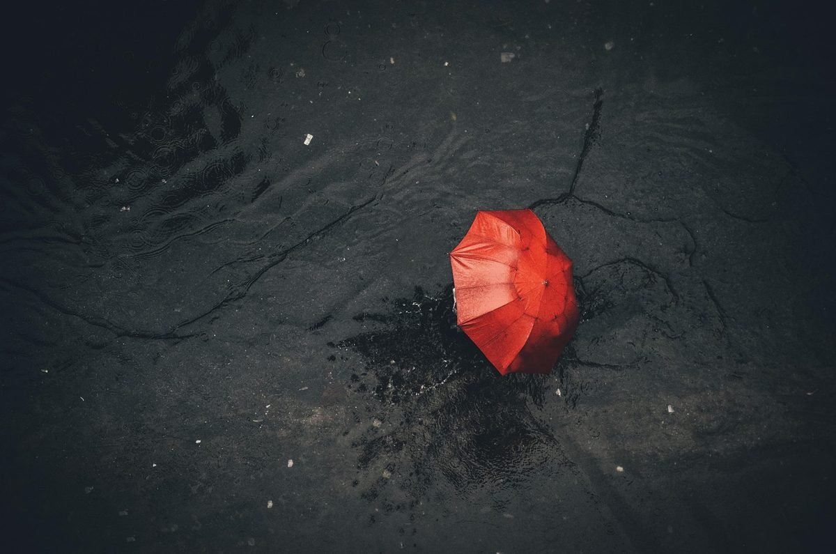 Red umbrella on dark water, a symbol of do you need umbrella insurance