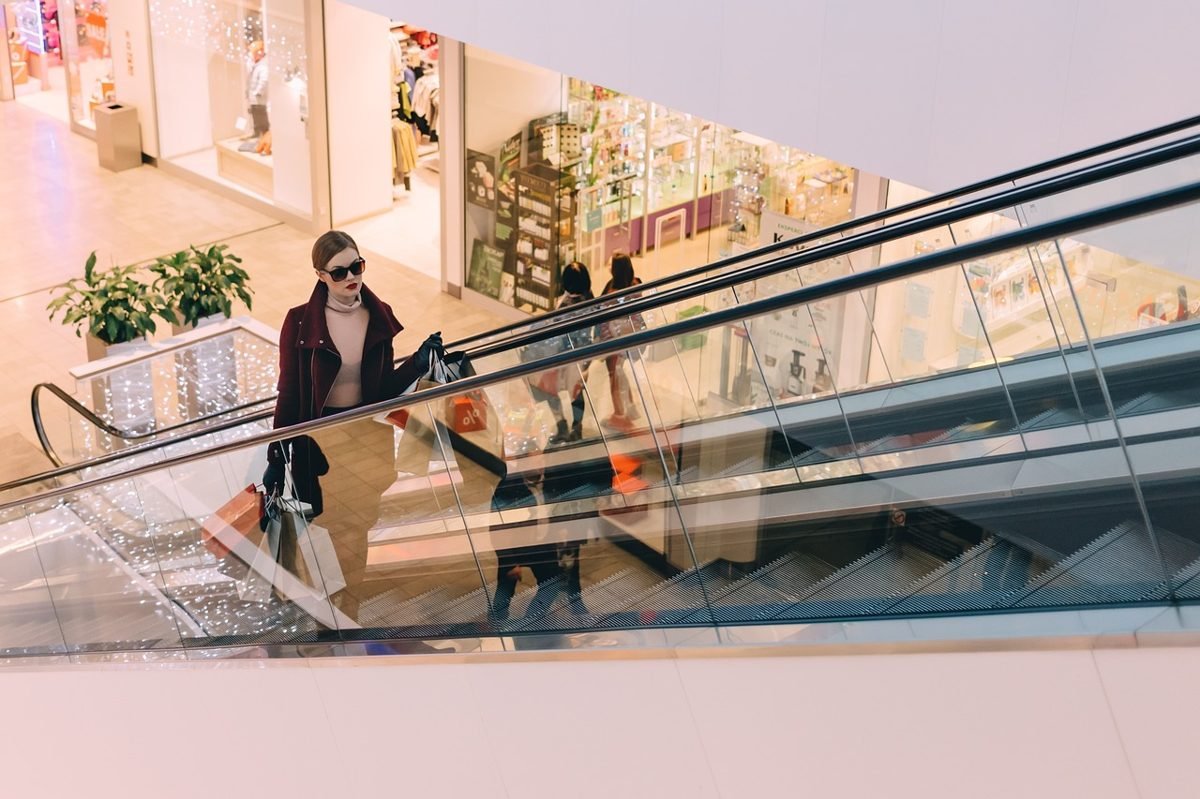 Shopper on an escalator in a mall learning to stop impulse buying