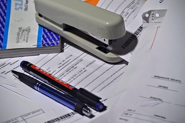 Stapler, pen and paperwork, checking each W-2 form box