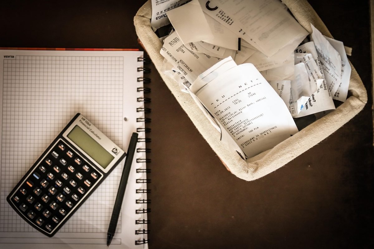 Notebook, calculator and receipts used to start a paycheck to paycheck budget