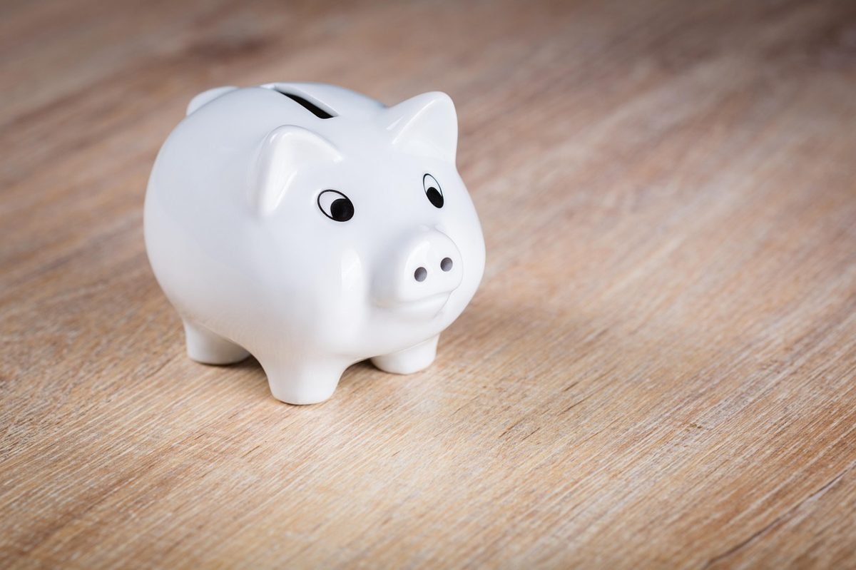 White piggy bank on a table, saving money to lower car insurance rates